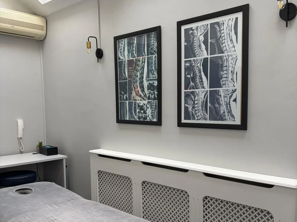 Treatment room at Spine Plus Chigwell, with treatment couch and framed spinal MRI scans